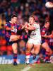 Andrew Johns gets a kick away despite pressure.